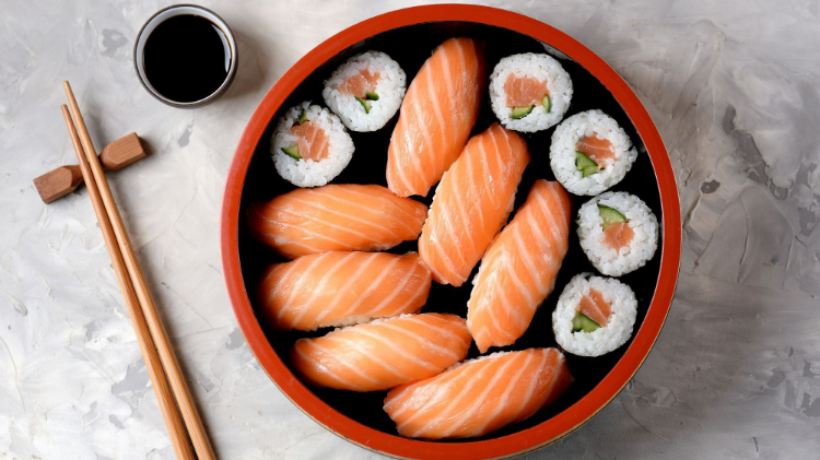 Salmon sushi and maki in a red-rimmed bowl