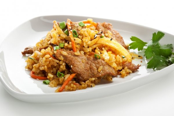Fried rice with meat and vegetables on a white plate